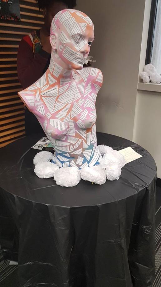 Mannequin bust covered suffocatingly in cutouts of print paper.